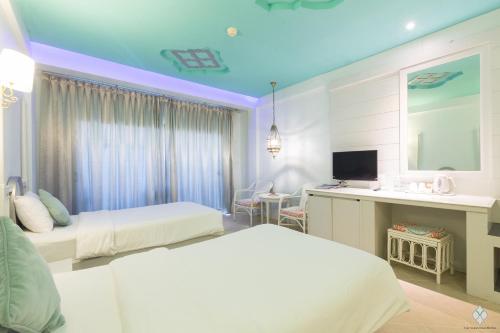 a bedroom with two beds and a desk with a television at The Verandah - SHA Extra Plus in Ao Nang Beach