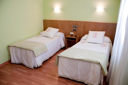 a room with two beds and a wooden floor at Hostal Restaurante La Cepa in Cariño