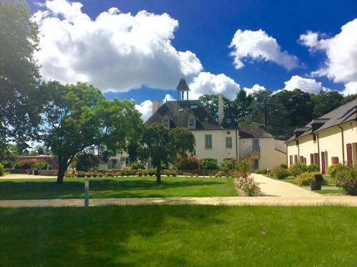 a large white house with a tower on a lawn at La Pommeraie in Bruz