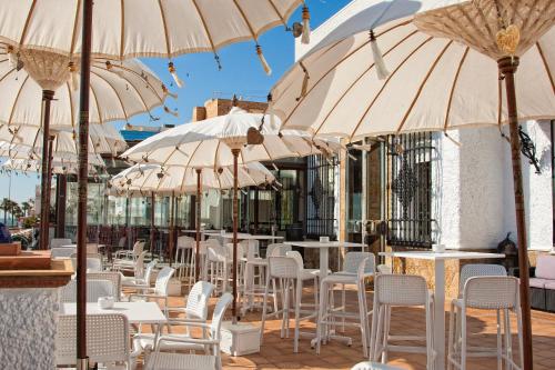 a row of tables and chairs with umbrellas at Hotel Playa de Regla in Chipiona