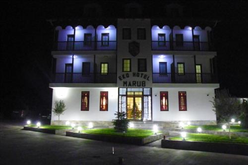 a large white building with a sign on it at night at Hotel Marub in Rubik