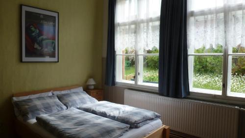ein Bett in einem Schlafzimmer mit zwei Fenstern in der Unterkunft Alte Schule in Tambach-Dietharz