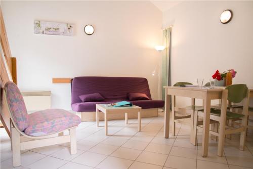 a living room with a purple couch and a table at Village de gîtes de Blajoux in Quézac