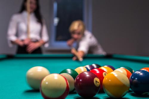 a woman standing behind a pool table with cue balls at Sodyba Ignė in Druskininkai