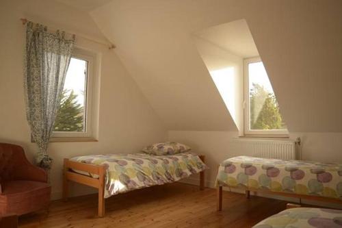 a bedroom with two beds and a chair and two windows at Tagar'étape in Étables-sur-Mer