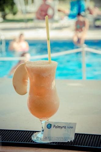 a drink sitting on a table next to a pool at Palmyra Hotel in Nydri
