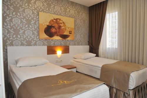 トラブゾンにあるQamar Prestige Suitesのベッド2台が備わる客室で、壁には絵画が飾られています。