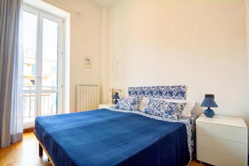 a bedroom with a blue bed and a large window at Casa Vacanze Oneglia in Imperia