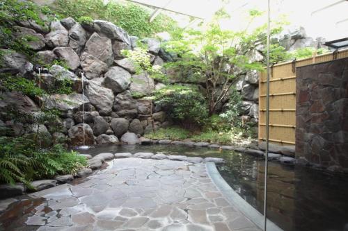 einen Garten mit einer Felswand und einem Teich in der Unterkunft Cent Core Yamaguchi in Yamaguchi