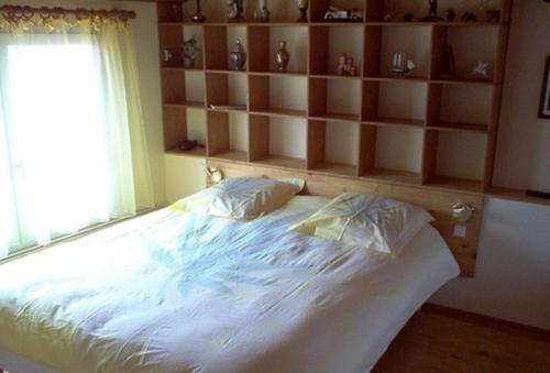 a bedroom with a white bed with a window and shelves at Chambres d'Hôtes La Forterie in Vairé
