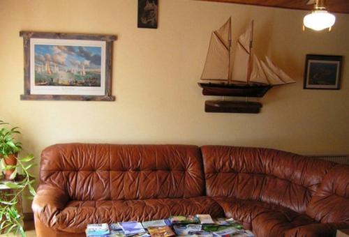 a brown leather couch in a living room with a boat on the wall at Chambres d'Hôtes La Forterie in Vairé