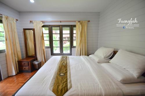 a large white bed in a room with a window at Fueng Fah Riverside Gardens Resort in Mae Rim