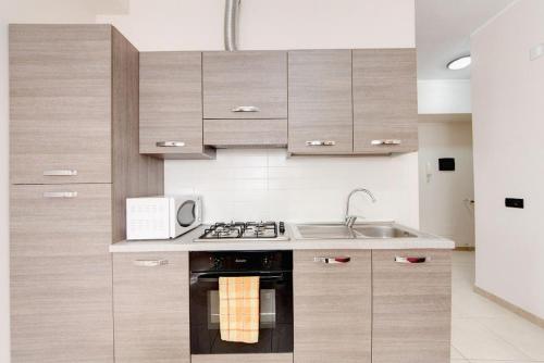 una cucina con armadi in legno, piano cottura e forno a microonde di Olimpo Apartments St John in Lateran a Roma