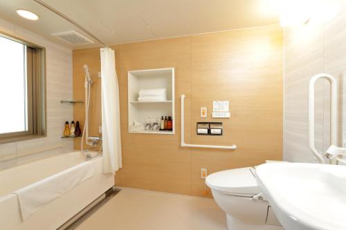 a bathroom with a tub and a toilet and a sink at Hiyori Hotel Maihama in Urayasu