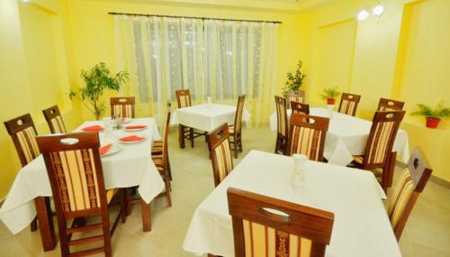 a dining room with white tables and wooden chairs at Camves Inn in Sighetu Marmaţiei