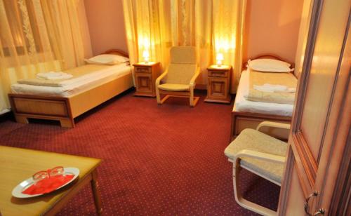 a room with two beds and a table and chairs at Camves Inn in Sighetu Marmaţiei