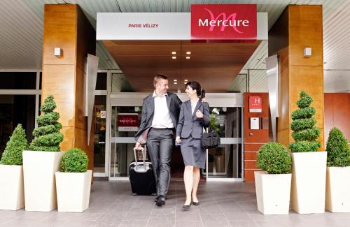 a man and woman walking in front of a store at Mercure Paris Velizy in Vélizy-Villacoublay