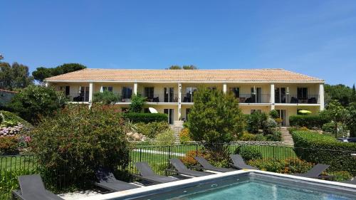 a building with chairs and a pool in front of it at Résidence Le Home in Calvi