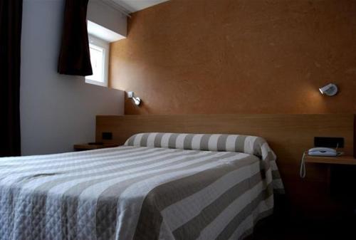 a bedroom with a bed with a striped blanket at Hôtel de France in Le Bessat