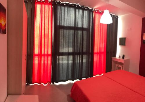 a bedroom with red curtains and a large window at Mirtos Apartments in Myrtos