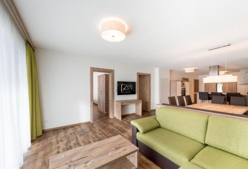 a living room with a green couch and a table at A Casa Saphir Appartement-Hotel in Sölden