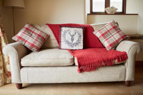 a couch with two pillows and a red blanket at Dallow Hall Barns in Grantley