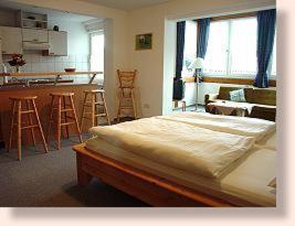 a bedroom with a large bed and a kitchen at Hotel Garni Burgstemmer Hof in Burgstemmen