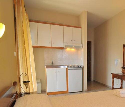 a small kitchen with white cabinets and a sink at Agnanti Studios in Panagia