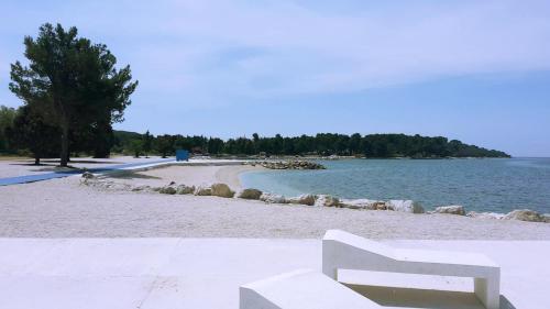 a white bench sitting on a beach next to the water at Apartment Ruby in Pula