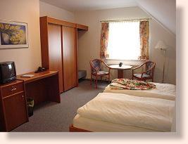 a hotel room with two beds and a table and a window at Hotel Garni Burgstemmer Hof in Burgstemmen