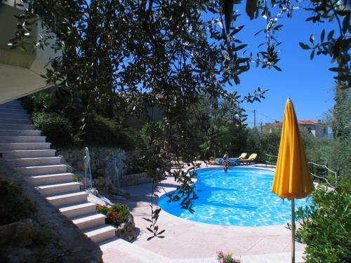 een zwembad met een gele parasol en een trap bij Villa Giada in Torri del Benaco