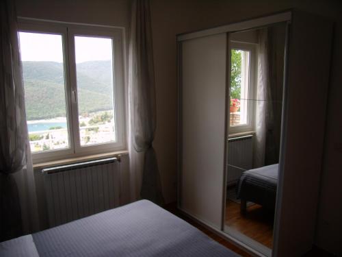 a bedroom with a mirror and a window with a view at Apartments Alma in Rabac