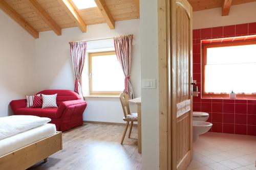 a bathroom with a red couch and a red chair at Coronata Haus in Roncegno