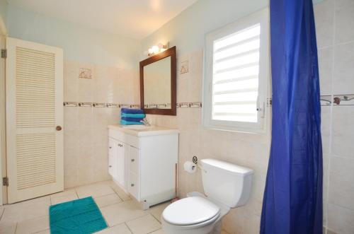 a bathroom with a toilet and a sink and a mirror at Pelican Pearl in Simpson Bay