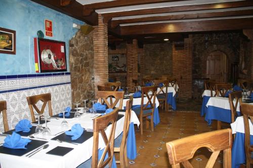 a dining room with white tables and blue napkins at Hotel Carvajal in Torrejón el Rubio
