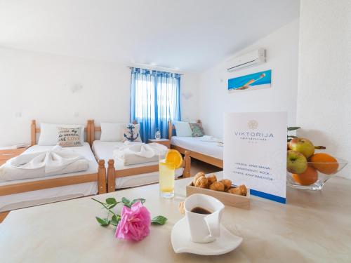 una habitación con 2 camas y una mesa con un bol de fruta en Apartments Viktorija, en Petrovac na Moru