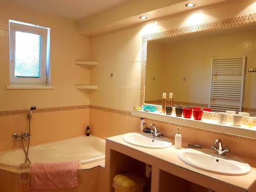 een badkamer met 2 wastafels, een bad en een spiegel bij Penzion Termál in Podhájska