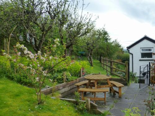 einen Picknicktisch in einem Garten neben einem Haus in der Unterkunft Bryn Ffynnon Holiday Cottage Llanrwst in Llanrwst
