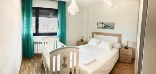- une chambre avec un lit blanc et une fenêtre dans l'établissement Alojamiento La Rosaleda, à Ponferrada