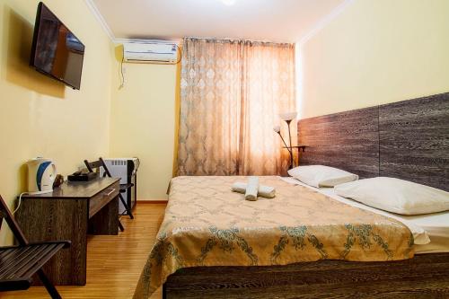 een slaapkamer met een bed, een bureau en een televisie bij Bereket in Astana