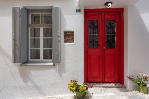 a red door on a white building with flowers at Evagelia's deluxe villa-Roof Top Jacuzzi in Skopelos Town
