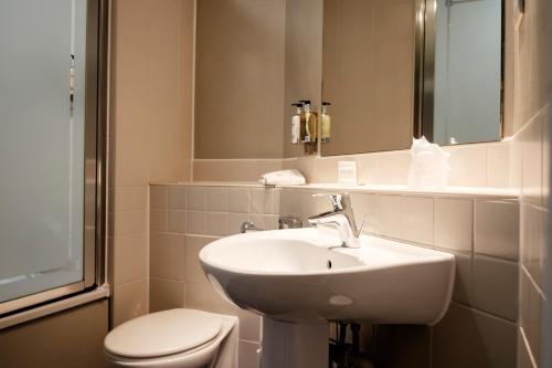 bagno con lavandino, servizi igienici e specchio di The Mad Hatter Hotel a Londra