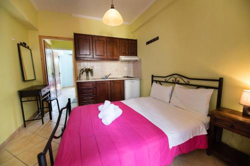 a bedroom with a large bed with a pink blanket at Argo Apartments in Vasiliki