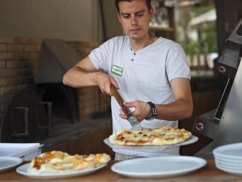 un hombre cortando una pizza con una espátula en Huttopia Gorges du Verdon, en Castellane