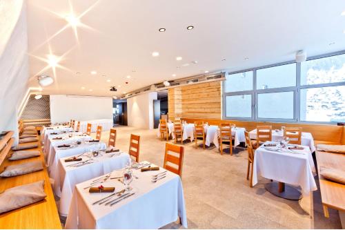 a dining room with white tables and chairs at Horsky Hotel Sliezsky Dom in Vysoké Tatry