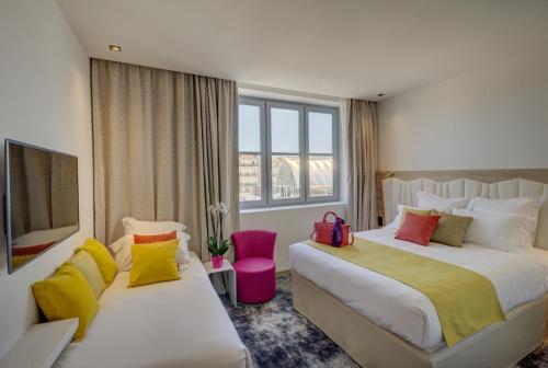 ein Hotelzimmer mit 2 Betten und bunten Kissen in der Unterkunft Best Western Plus Comedie Saint Roch in Montpellier