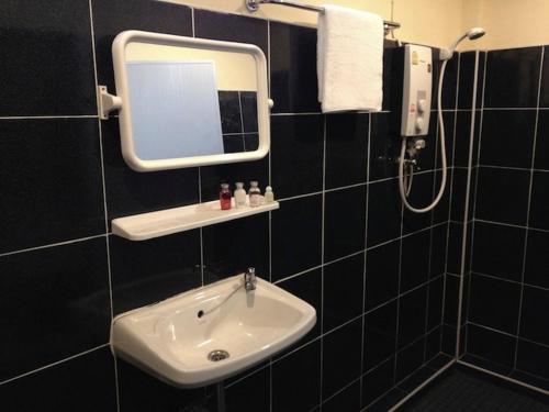 La salle de bains est pourvue d'un lavabo et d'un miroir. dans l'établissement Areeya Resort, à Watthana Nakhon