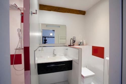 La salle de bains blanche est pourvue d'un lavabo et d'un miroir. dans l'établissement Les Tournelles - Chambres d'hôtes, à Saint-Mesmes