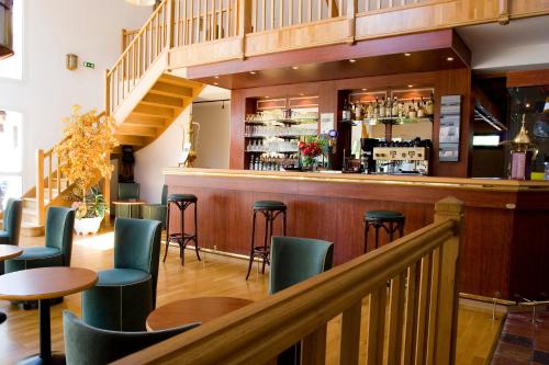 a bar with green chairs and tables in a restaurant at Hotel ARBOR - Les Hunaudieres - Le Mans Sud - Mulsanne in Mulsanne