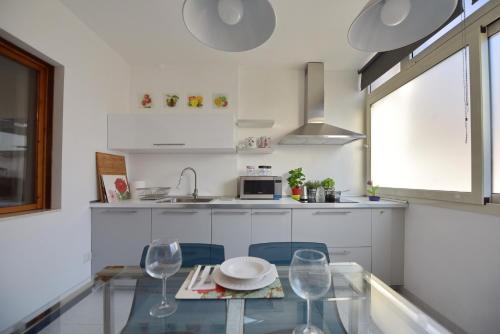 a white kitchen with a glass table and chairs at Stella Marina in Quartu SantʼElena